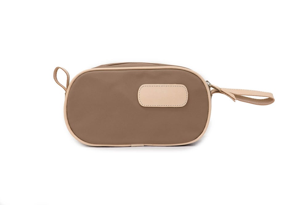 A person holding a black and brown vinyl coated canvas shaving kit with natural leather trim and straps, featuring a zippered closure and the brand name 'Lewis' on the front.