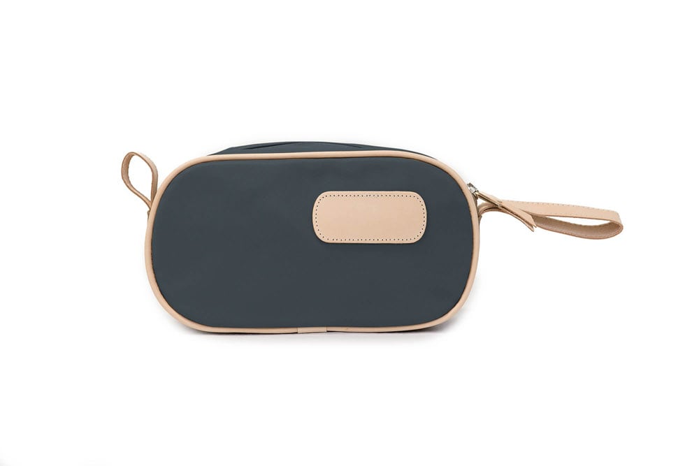 A person holding a black and brown vinyl coated canvas shaving kit with natural leather trim and straps, featuring a zippered closure and the brand name 'Lewis' on the front.